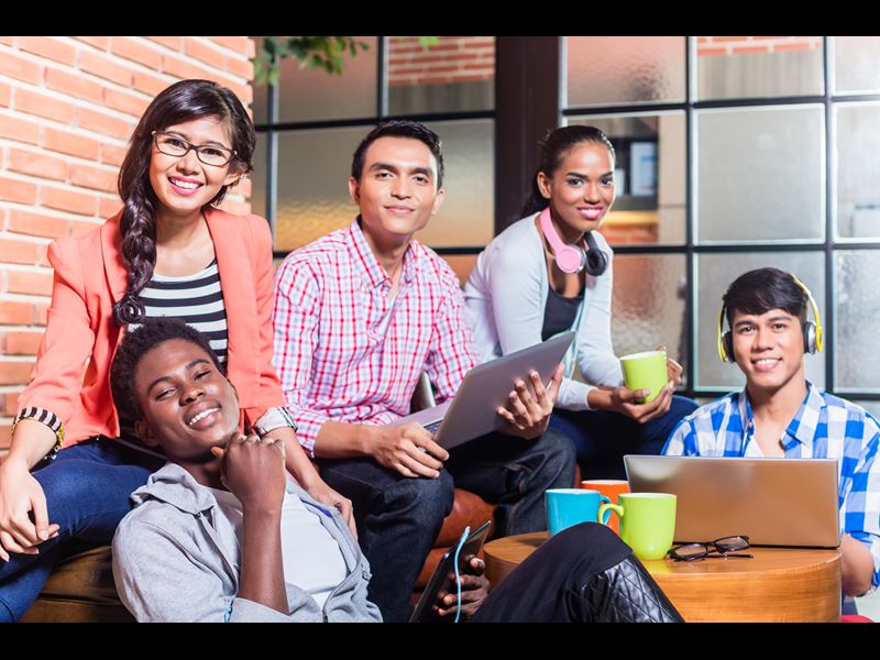 Group of five people at coffee house, smiling at camera