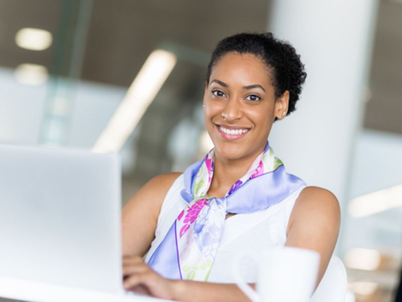 Woman in front of laptop, smiling at camera
