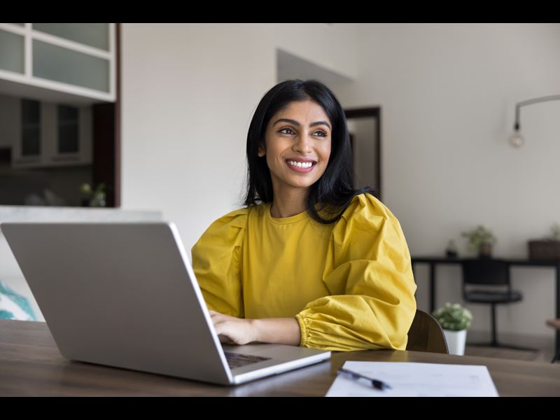 Woman Smiling While Working On Laptop
