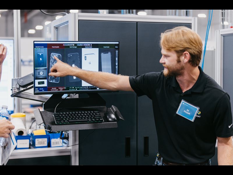 Assurant employee pointing at a computer screen in Device Care Center