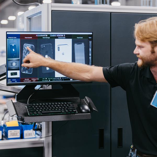 Assurant employee pointing at a computer screen in Device Care Center