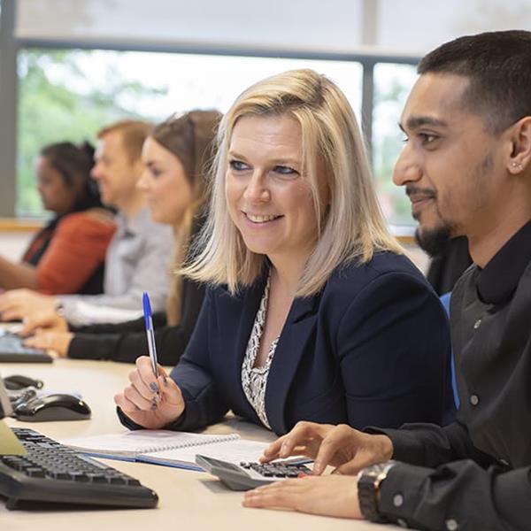 Two Assurant employees in the foreground working on a computer and three employees in the background