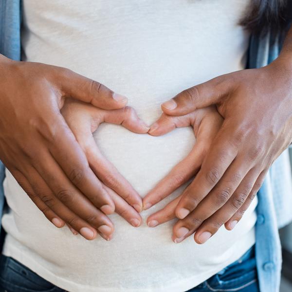 Assurant Blog Image: Couple holding hands in heart of woman's pregnant belly