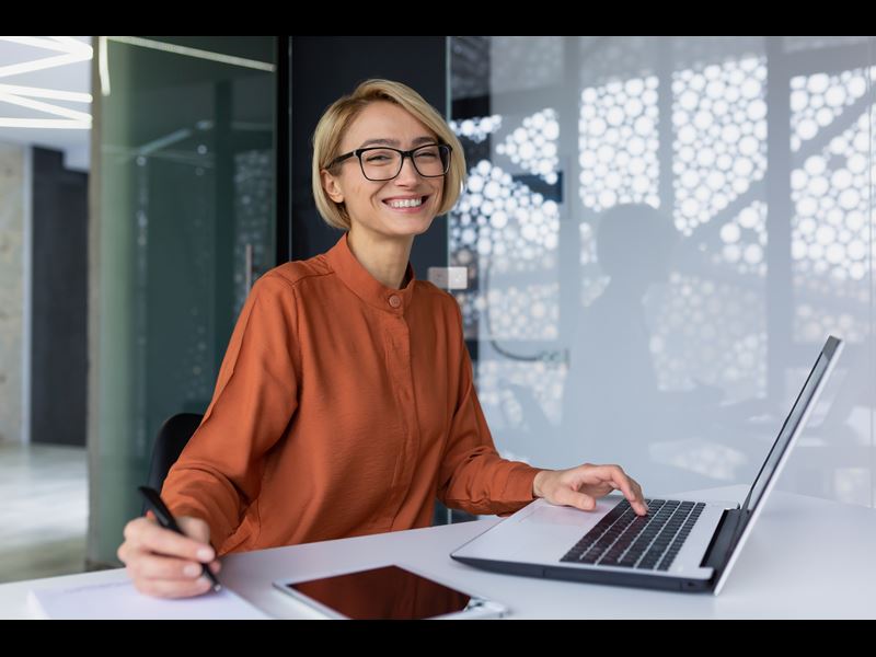 Woman Smiling While Typing On Laptop