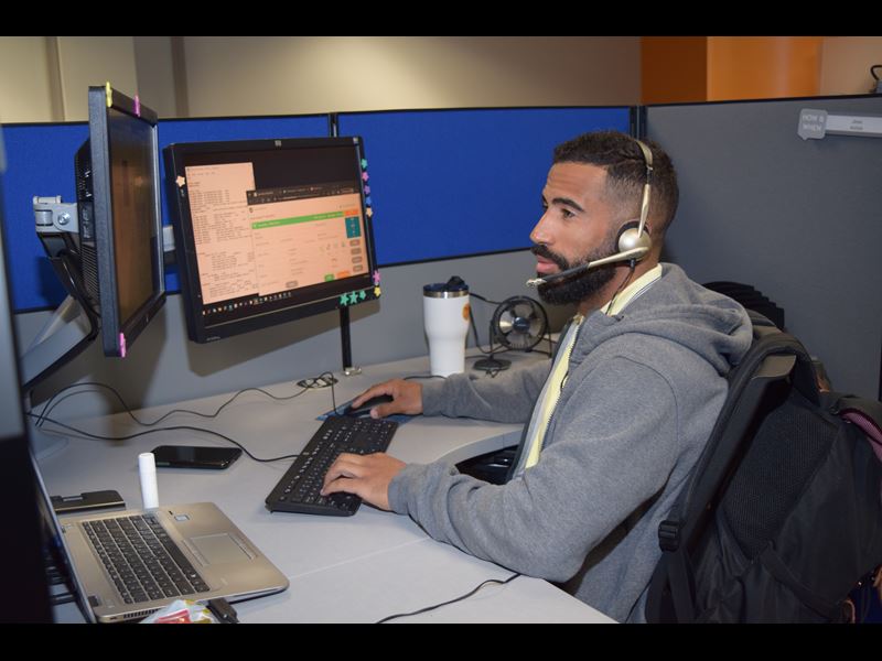 Assurant employee working from desk in office with headset on
