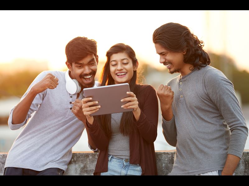 Three people smiling and looking at tablet