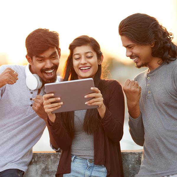 Three people smiling and looking at tablet