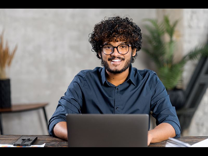 Young Man Smiling While On Laptop