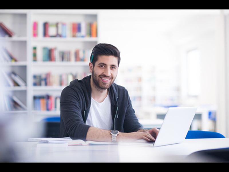 Man working in front of laptop, smiling at camera