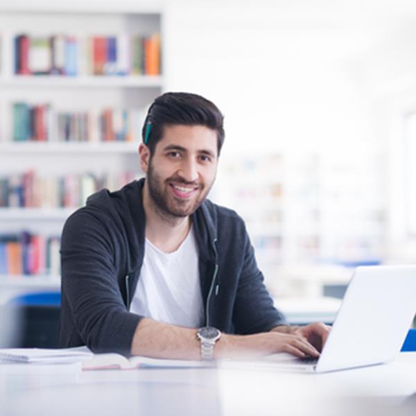 Man working in front of laptop, smiling at camera