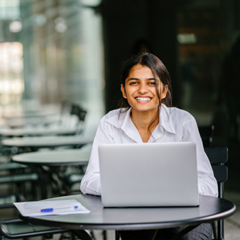 Smiling woman sitting at cafe table in front of laptop