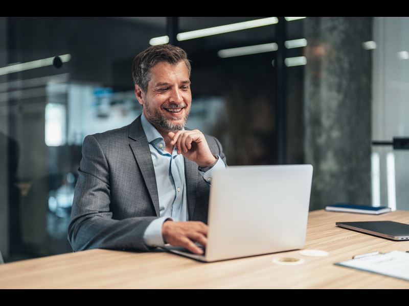 Mature Male Professional Smiling And Looking At Laptop