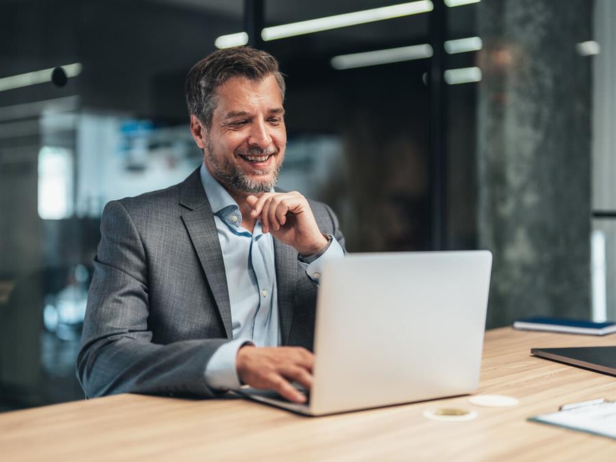 Mature Male Professional Smiling And Looking At Laptop