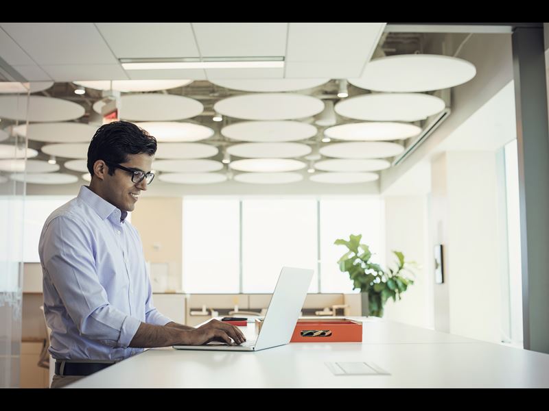 Man with glasses smiling and working on laptop