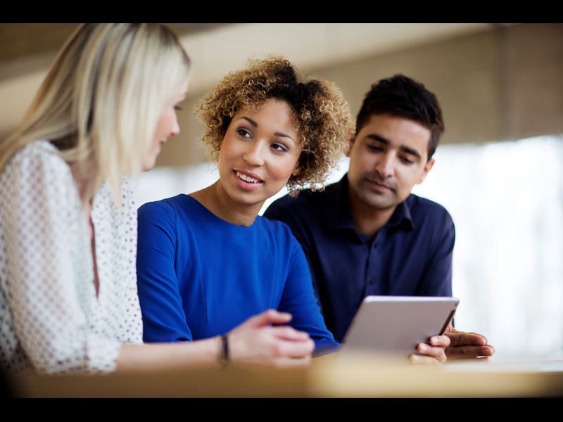 Three Professionals Talking And Holding Tablet