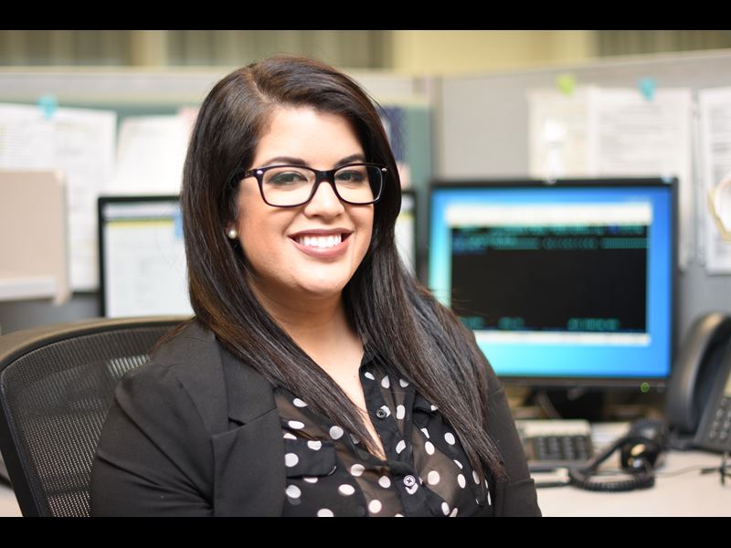 Assurant employee, Amanda Mayor, smiling while sitting at desk in office