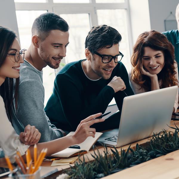 Group of five employees looking at laptop together and smiling