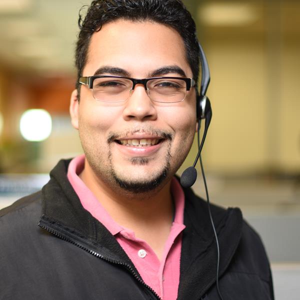 Assurant employee, Erwin Guzman, smiling at camera while wearing headset in office