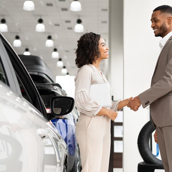 Two people shaking hands at car dealership