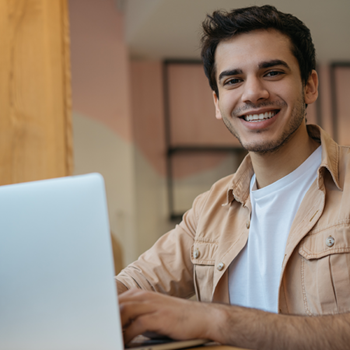 Man looking up from laptop to smile