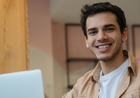 Man looking up from laptop to smile
