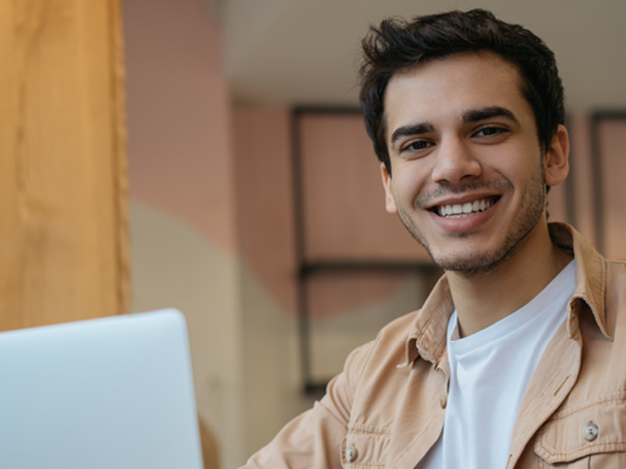 Man looking up from laptop to smile