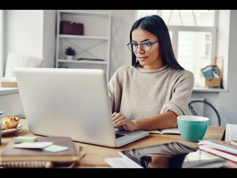 Woman working from home, looking at laptop