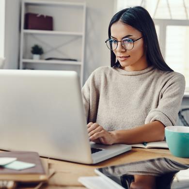 Woman working from home, looking at laptop