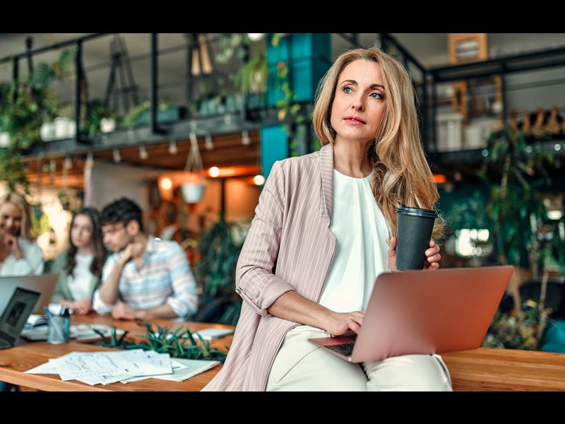 Woman Sitting On Desk With Laptop