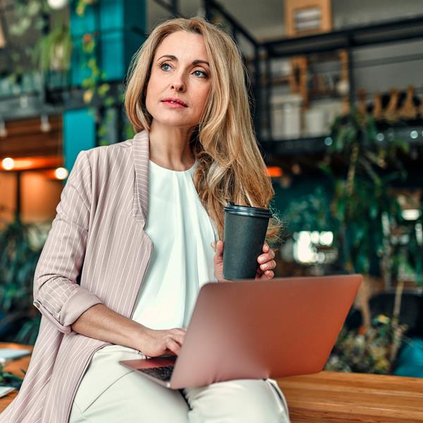 Woman Sitting On Desk With Laptop