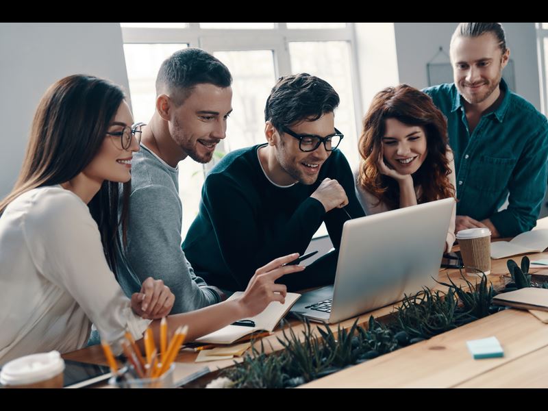 Group Of Professionals Smiling And Looking At Laptop