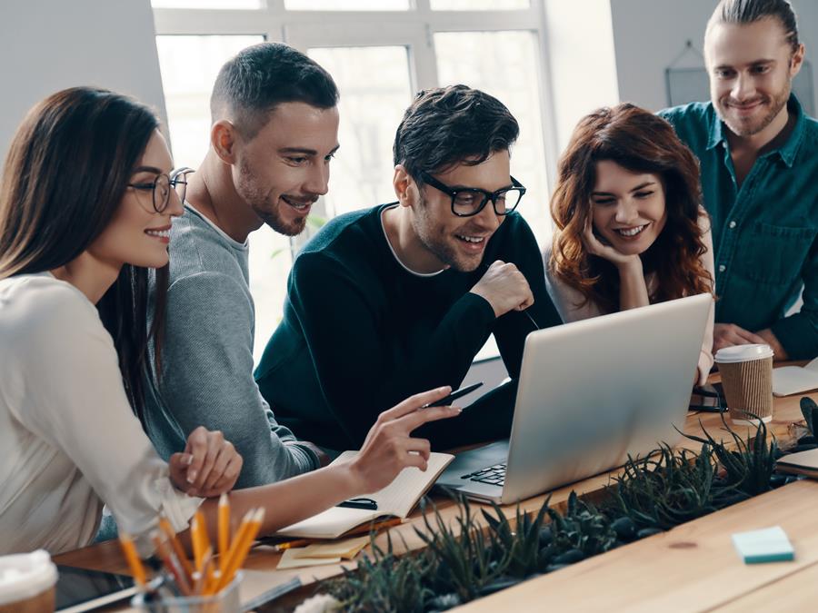 Group Of Professionals Smiling And Looking At Laptop