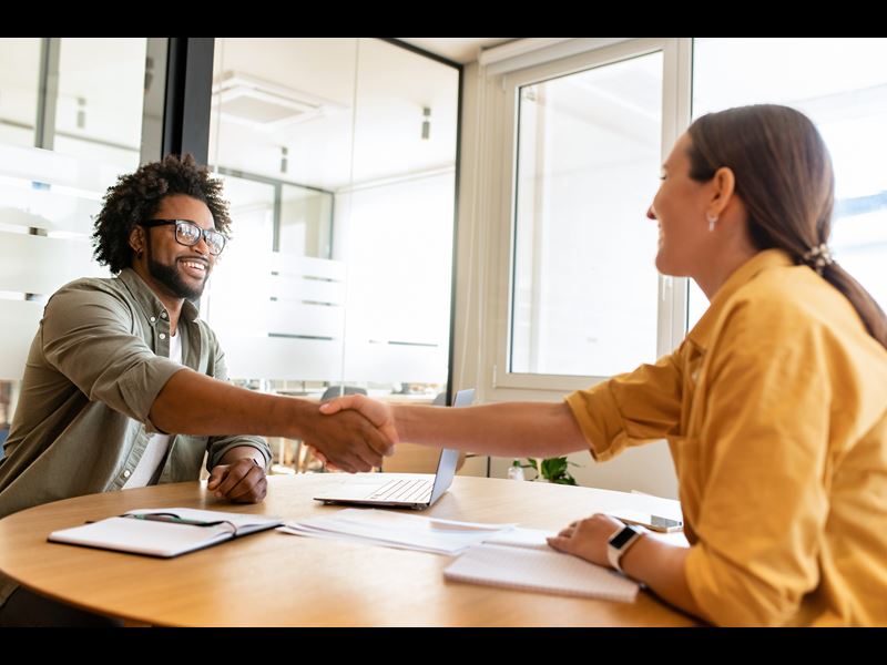 Man and woman shaking hands over table