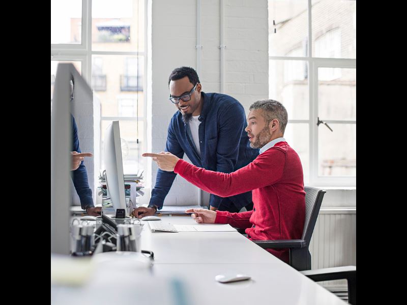 Employees looking at monitor and working together