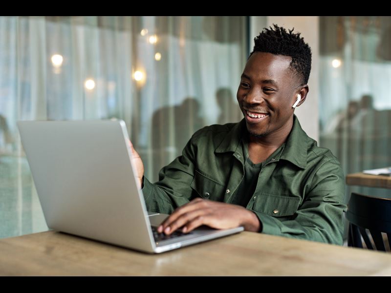 Man smiling at laptop with headphones in ears