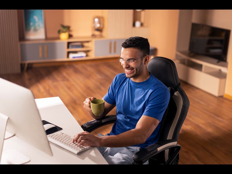 Man Holding Coffee Mug Smiling And Typing On Computer