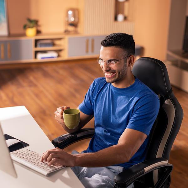 Man Holding Coffee Mug Smiling And Typing On Computer