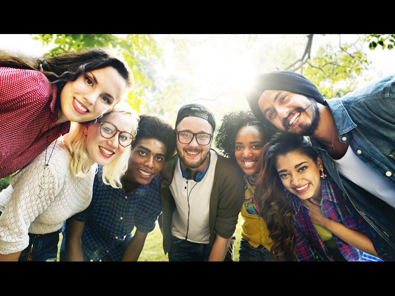Diverse group of seven people, standing together and smiling at camera