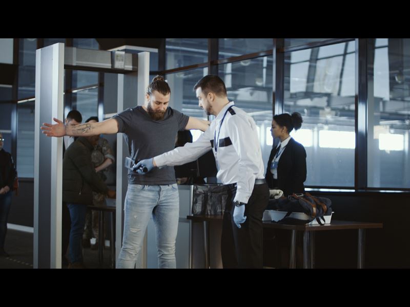 Security person scanning person with metal detector