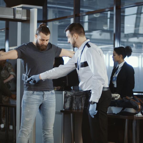 Security person scanning person with metal detector