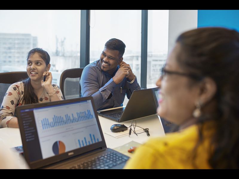 Smiling Professionals Sitting At Conference Table During Meeting