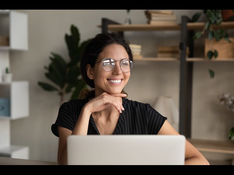 Woman working from home, smiling in front of a laptop