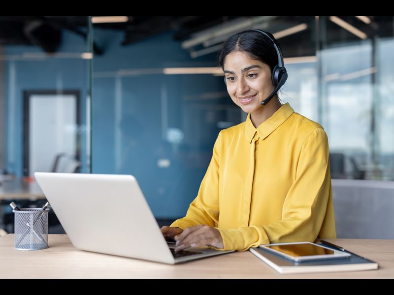 Woman On Headphones Smiling And Working On Laptop