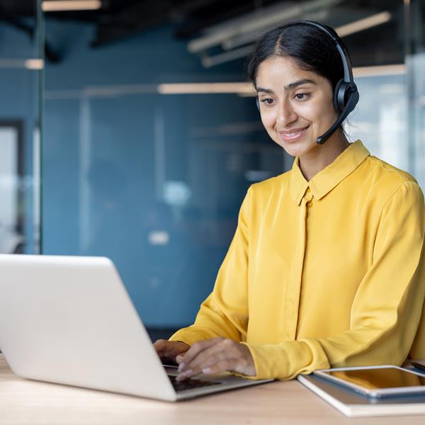 Woman On Headphones Smiling And Working On Laptop